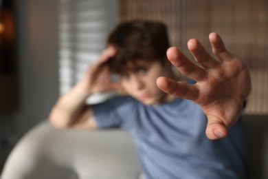 Photo of Teen problems. Upset teenage boy making stop gesture at home, selective focus