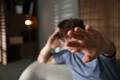 Photo of Teen problems. Upset teenage boy making stop gesture at home, selective focus