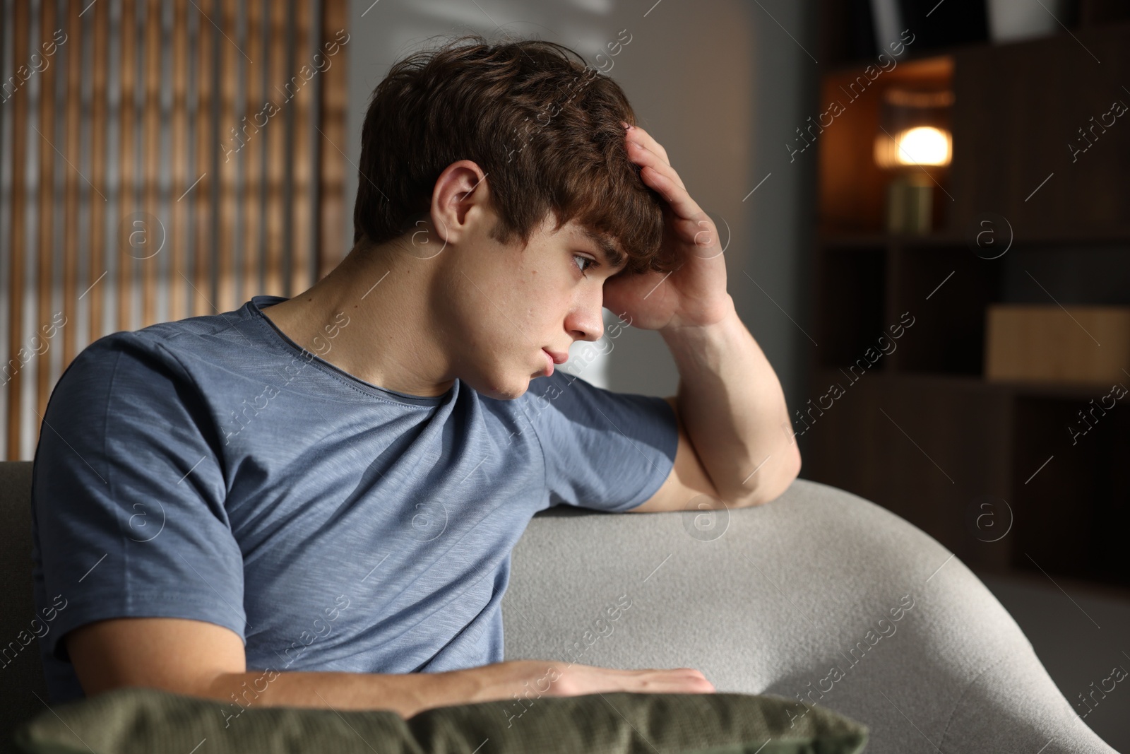 Photo of Teen problems. Upset teenage boy on sofa at home