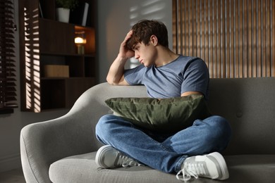 Photo of Teen problems. Upset teenage boy on sofa at home