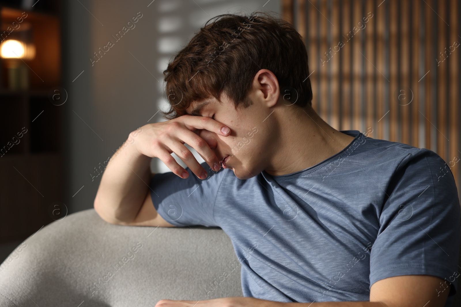 Teen problems. Upset teenage boy on sofa at home Photo of Teen problems. Upset teenage boy on sofa at home
