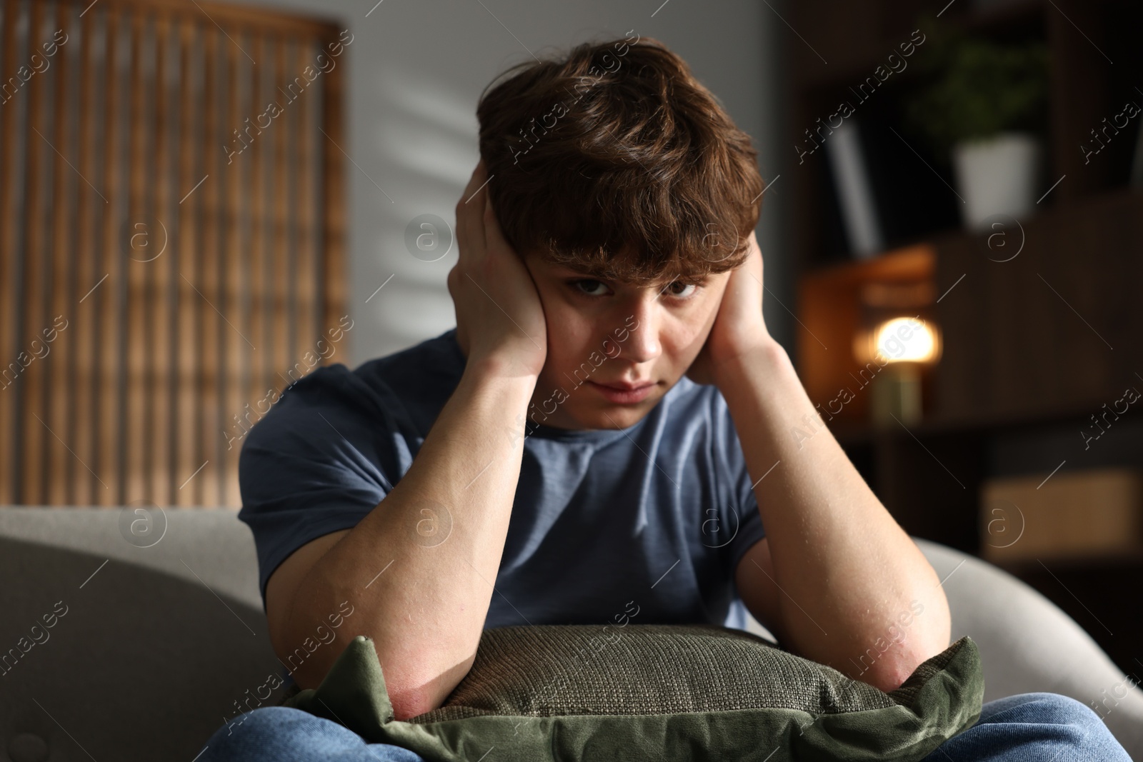 Teen problems. Upset teenage boy on sofa at home Photo of Teen problems. Upset teenage boy on sofa at home