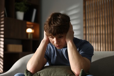 Photo of Teen problems. Upset teenage boy on sofa at home