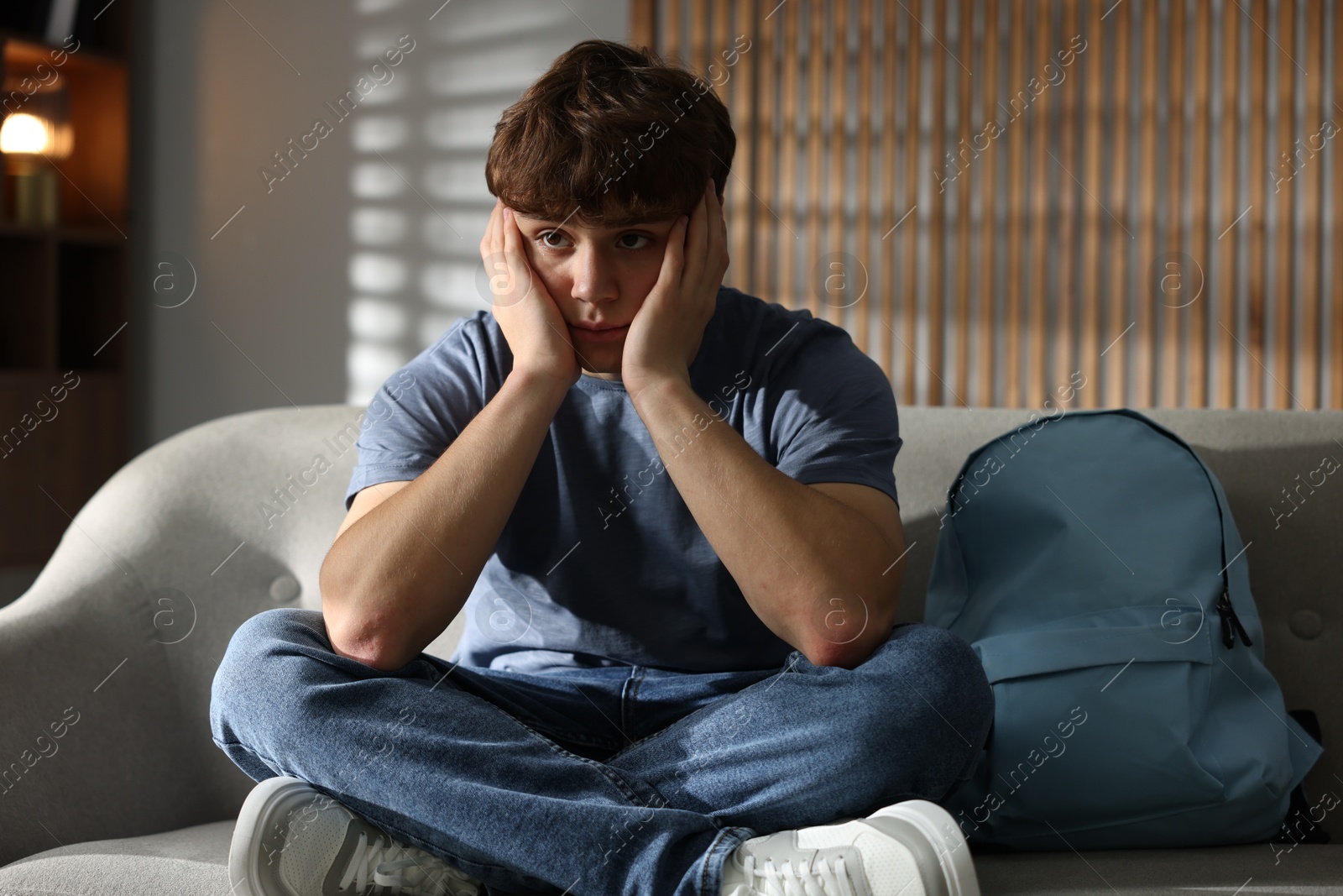Teen problems. Upset teenage boy on sofa at home Photo of Teen problems. Upset teenage boy on sofa at home