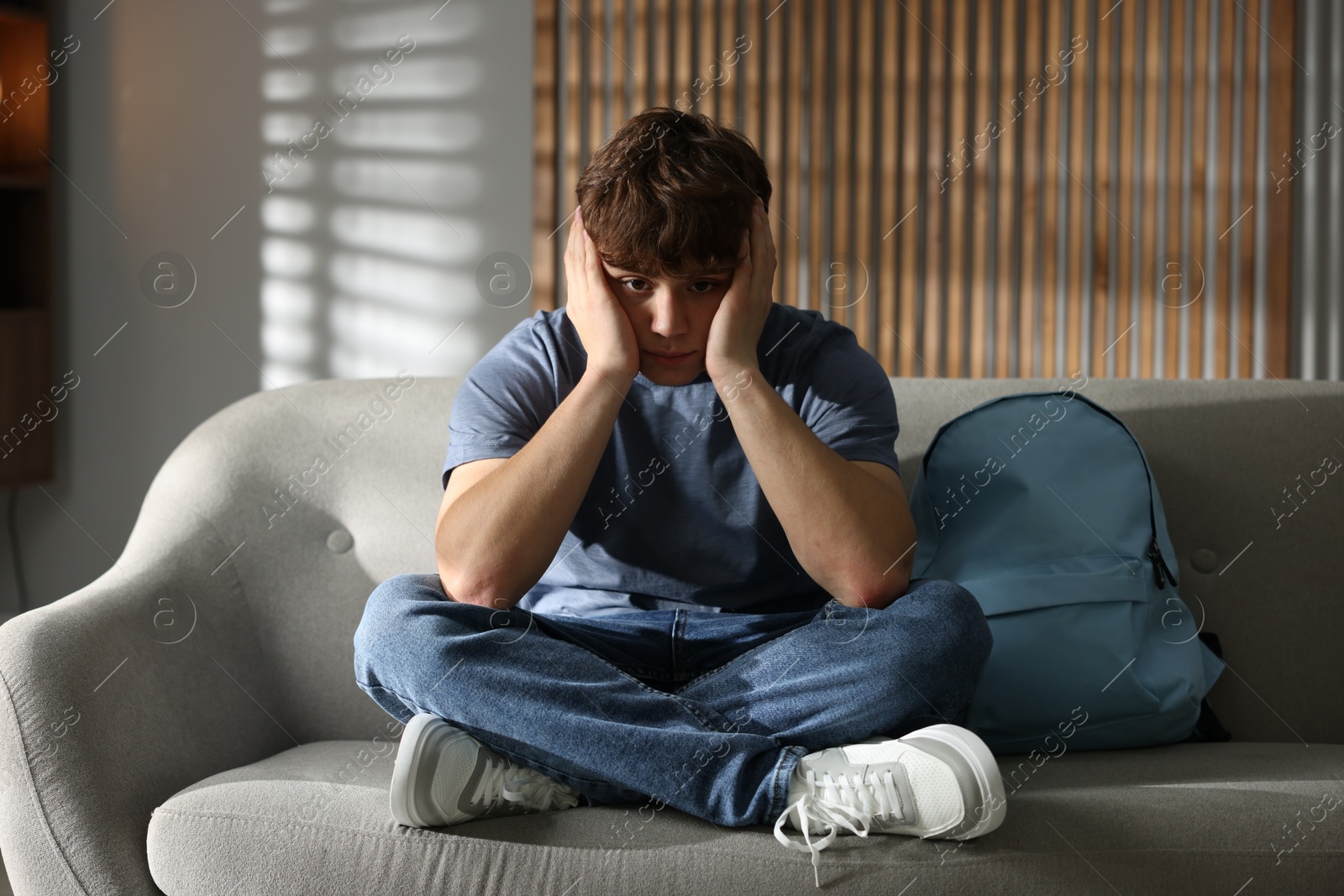 Teen problems. Upset teenage boy on sofa at home Photo of Teen problems. Upset teenage boy on sofa at home