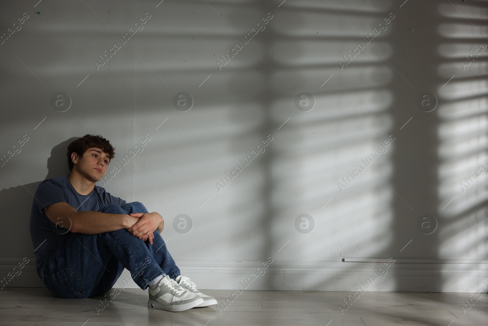Teen problems. Upset teenage boy near light wall indoors, space for text Photo of Teen problems. Upset teenage boy near light wall indoors, space for text