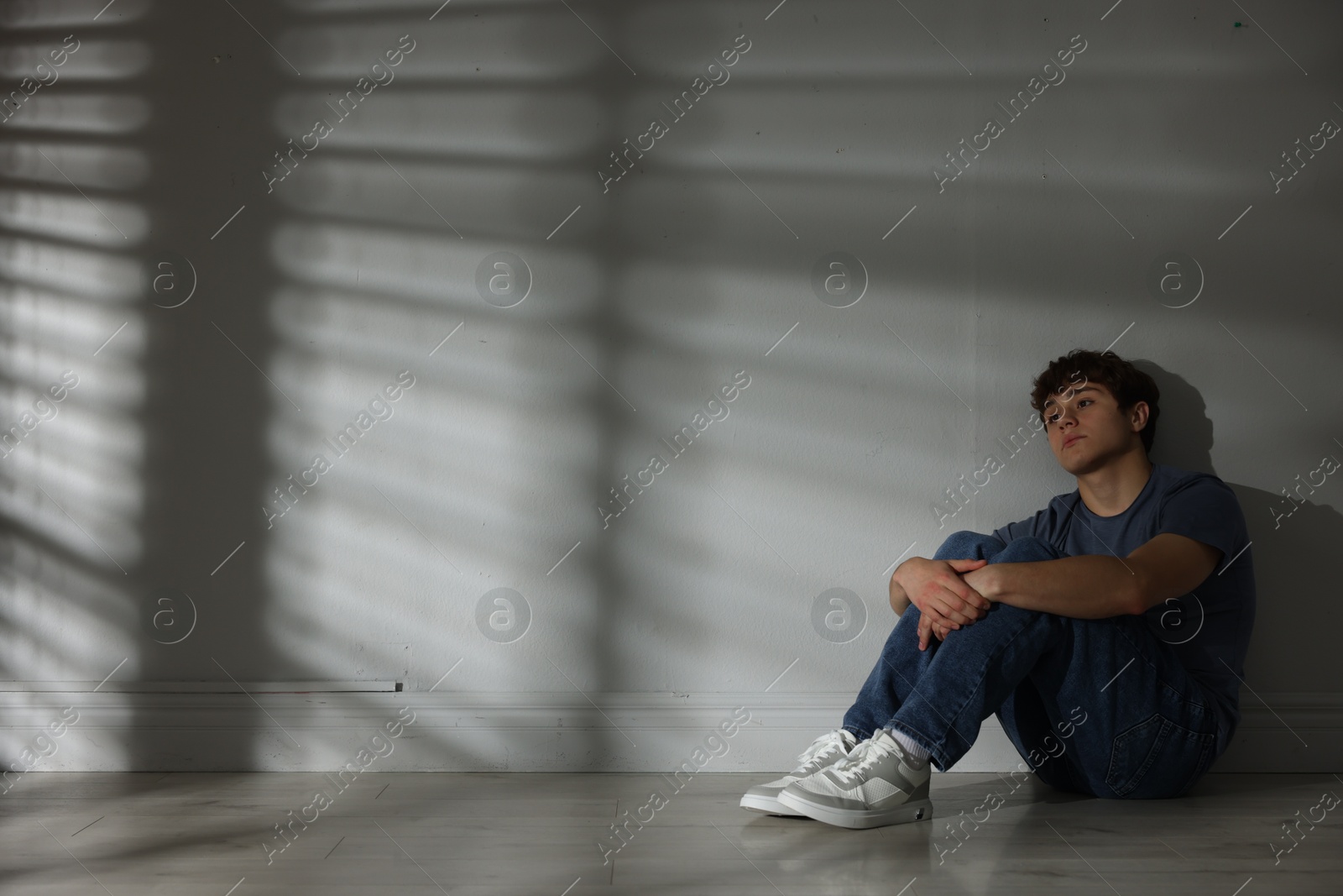 Teen problems. Upset teenage boy near light wall indoors, space for text Photo of Teen problems. Upset teenage boy near light wall indoors, space for text