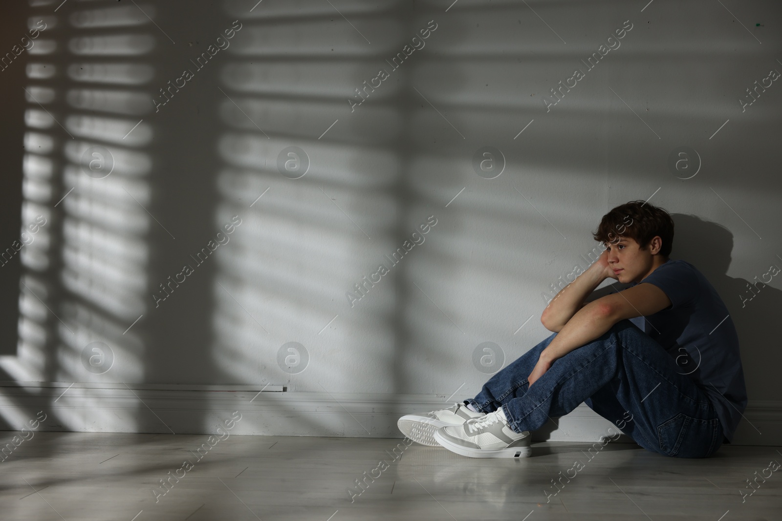 Teen problems. Upset teenage boy near light wall indoors, space for text Photo of Teen problems. Upset teenage boy near light wall indoors, space for text