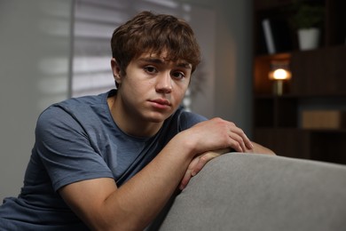 Photo of Teen problems. Upset teenage boy on sofa at home