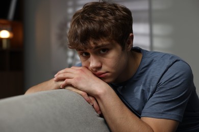 Photo of Teen problems. Upset teenage boy on sofa at home