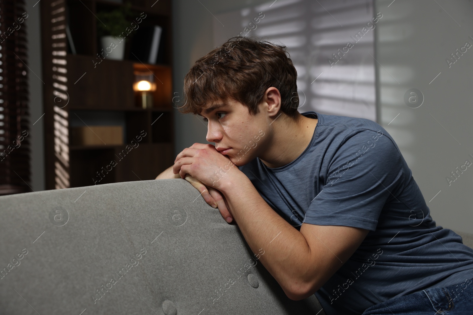 Teen problems. Upset teenage boy on sofa at home Photo of Teen problems. Upset teenage boy on sofa at home