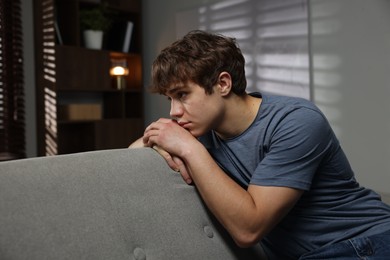 Photo of Teen problems. Upset teenage boy on sofa at home