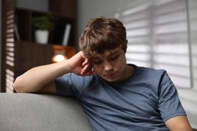 Photo of Teen problems. Upset teenage boy on sofa at home