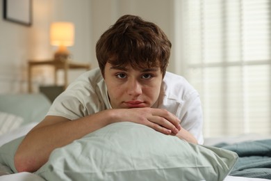 Photo of Teen problems. Upset teenage boy on bed at home
