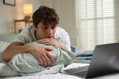 Photo of Teen problems. Upset teenage boy with laptop on bed at home