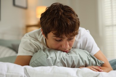 Photo of Teen problems. Upset teenage boy on bed at home