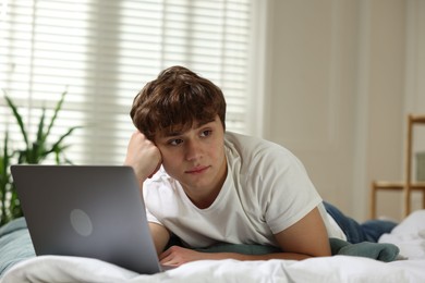Photo of Teen problems. Upset teenage boy with laptop on bed at home