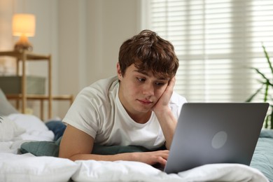 Photo of Teen problems. Upset teenage boy with laptop on bed at home