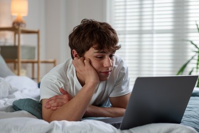 Photo of Teen problems. Upset teenage boy with laptop on bed at home