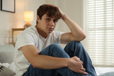 Photo of Teen problems. Upset teenage boy on bed at home