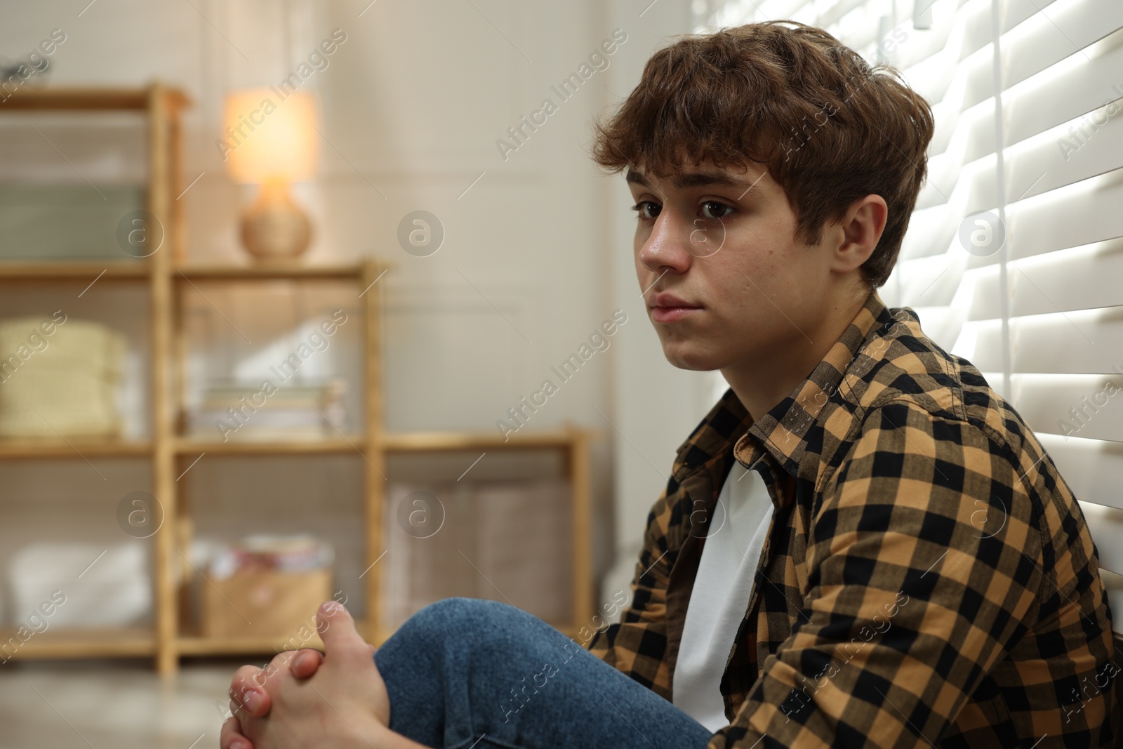 Teen problems. Depressed teenage boy near window at home, space for text Photo of Teen problems. Depressed teenage boy near window at home, space for text