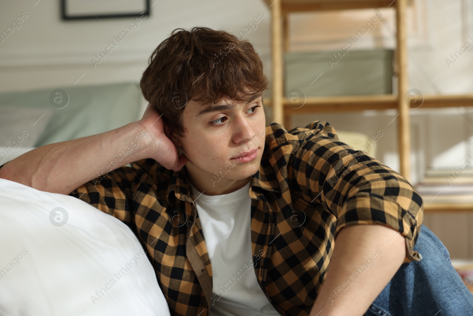 Teen problems. Upset teenage boy near bed at home Photo of Teen problems. Upset teenage boy near bed at home