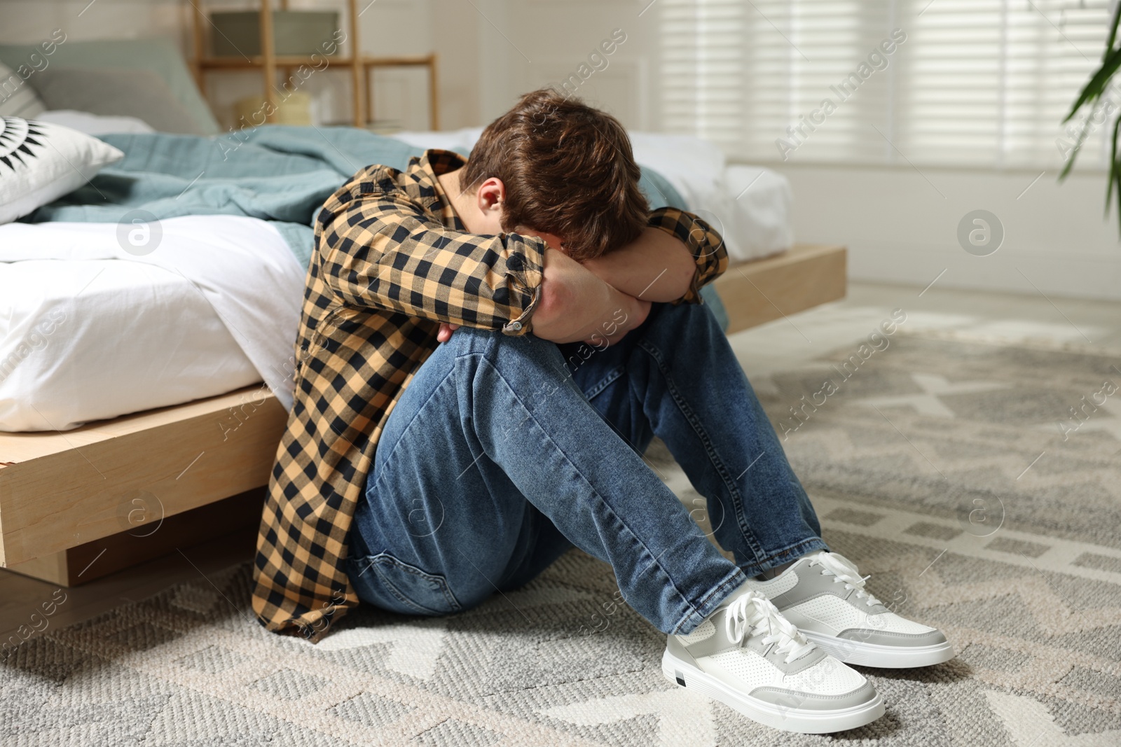 Teen problems. Depressed teenage boy on floor at home Photo of Teen problems. Depressed teenage boy on floor at home