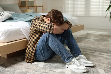 Photo of Teen problems. Depressed teenage boy on floor at home