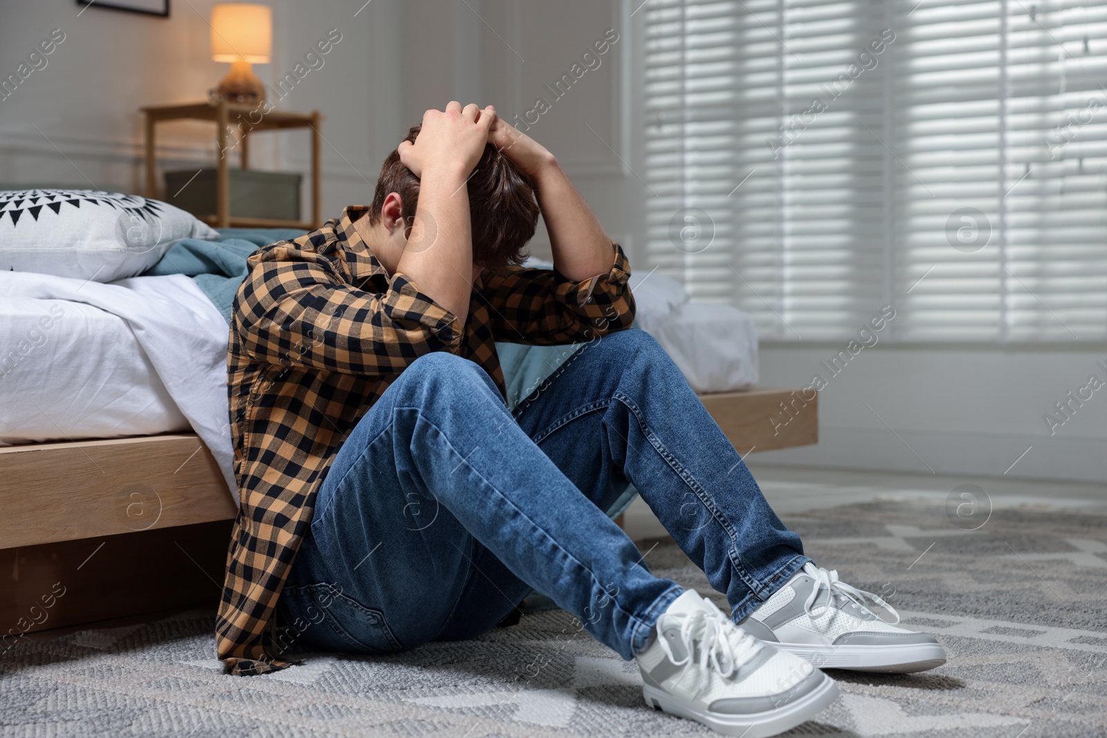 Teen problems. Depressed teenage boy on floor at home Photo of Teen problems. Depressed teenage boy on floor at home