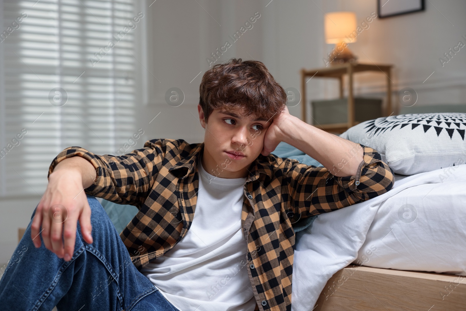 Teen problems. Upset teenage boy on floor at home Photo of Teen problems. Upset teenage boy on floor at home