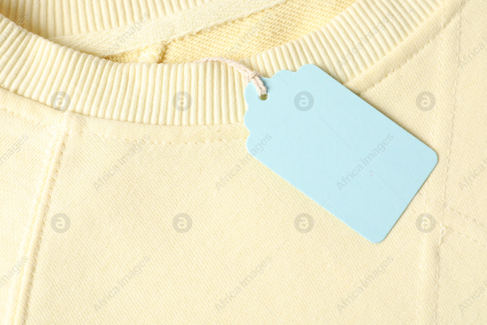 Cardboard tag on beige garment, top view Photo of Cardboard tag on beige garment, top view