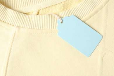 Photo of Cardboard tag on beige garment, top view