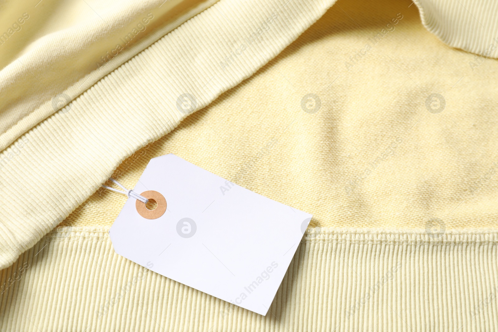 Cardboard tag on beige garment, top view Photo of Cardboard tag on beige garment, top view
