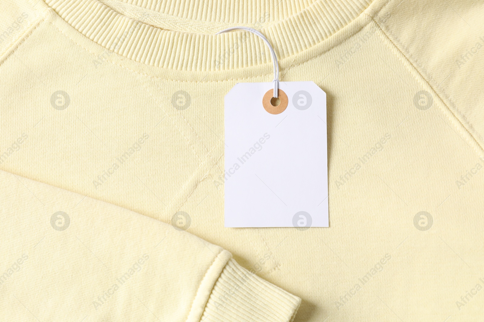 Cardboard tag on beige garment, top view Photo of Cardboard tag on beige garment, top view