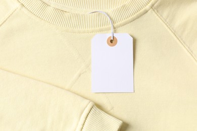 Photo of Cardboard tag on beige garment, top view