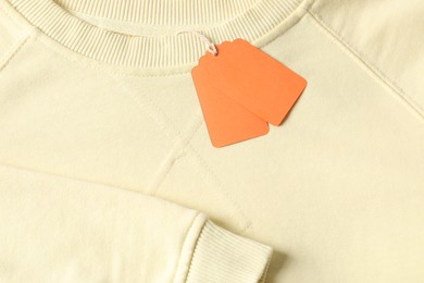 Photo of Cardboard tags on beige garment, top view