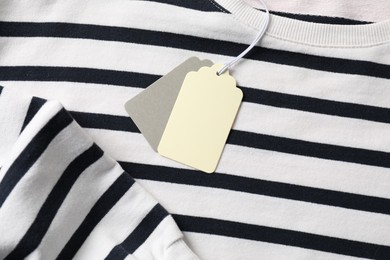 Photo of Cardboard tags on striped garment, top view