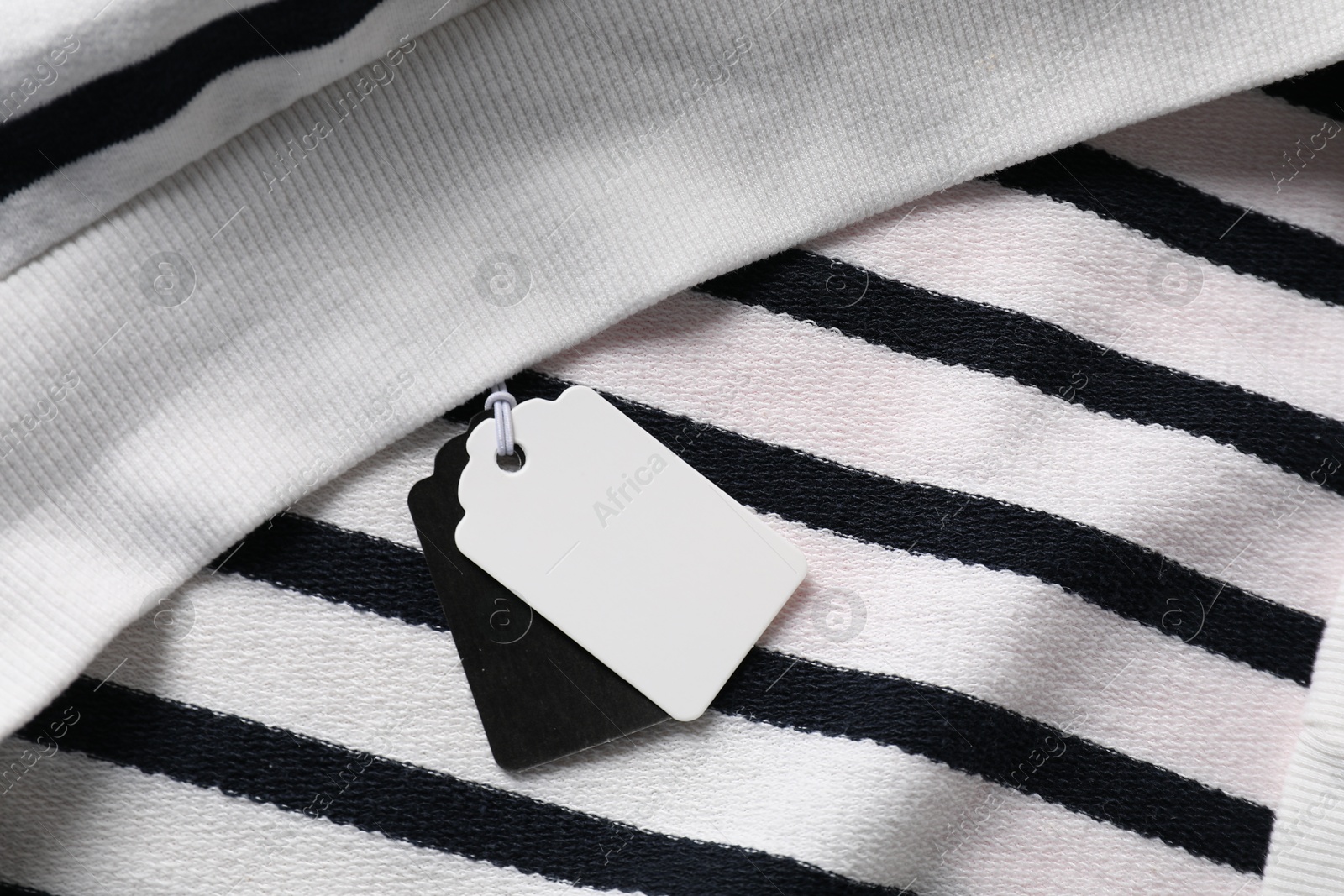 Cardboard tags on striped garment, top view Photo of Cardboard tags on striped garment, top view