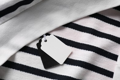Photo of Cardboard tags on striped garment, top view
