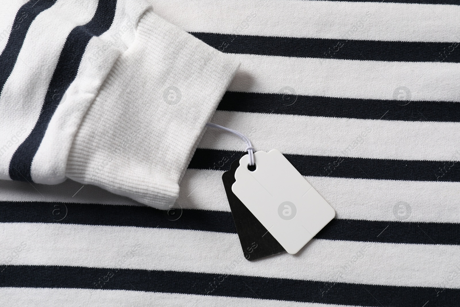 Cardboard tags on striped garment, top view Photo of Cardboard tags on striped garment, top view