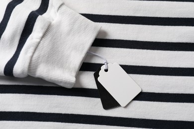Photo of Cardboard tags on striped garment, top view