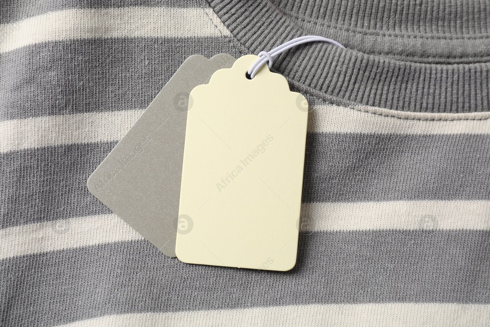 Cardboard tags on striped garment, top view Photo of Cardboard tags on striped garment, top view