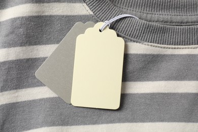 Photo of Cardboard tags on striped garment, top view