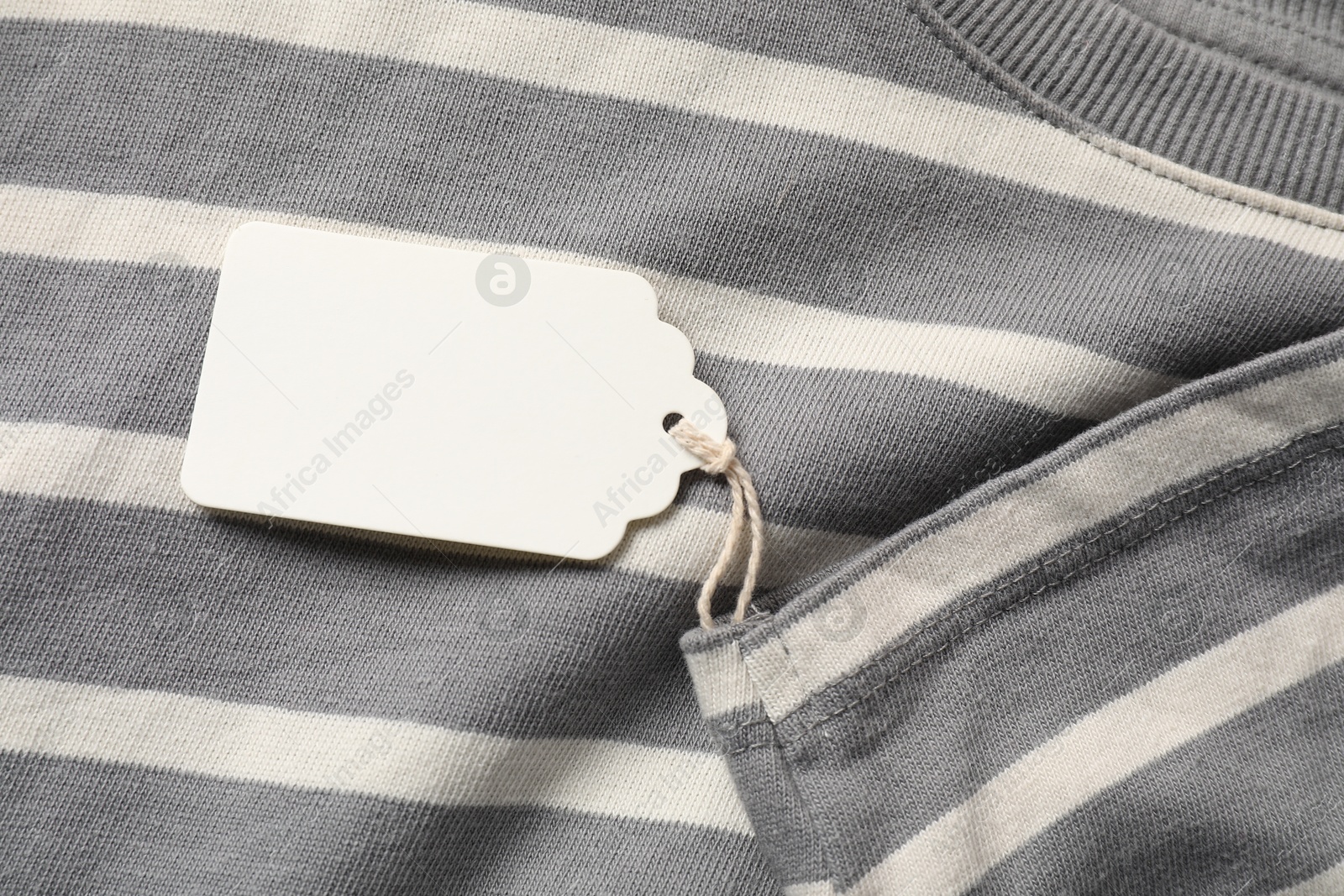 Cardboard tag on striped garment, top view Photo of Cardboard tag on striped garment, top view