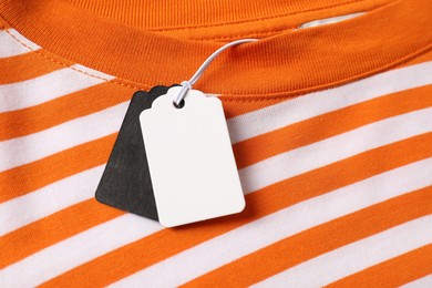 Photo of Cardboard tags on striped garment, top view