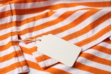 Photo of Cardboard tag on striped garment, closeup view
