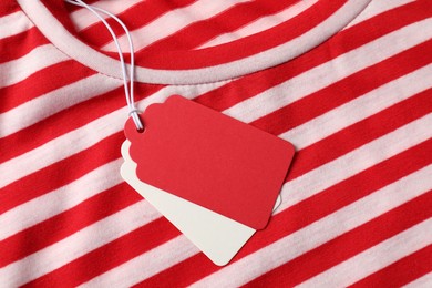 Photo of Cardboard tags on striped garment, top view