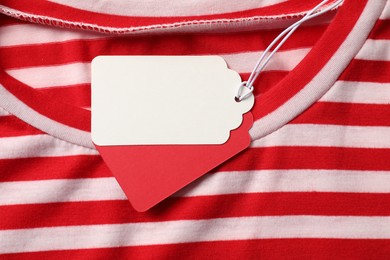 Photo of Cardboard tags on striped garment, top view