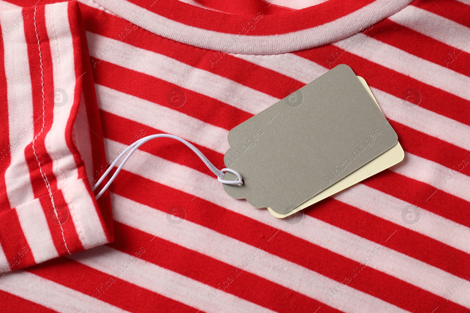 Cardboard tags on striped garment, top view Photo of Cardboard tags on striped garment, top view