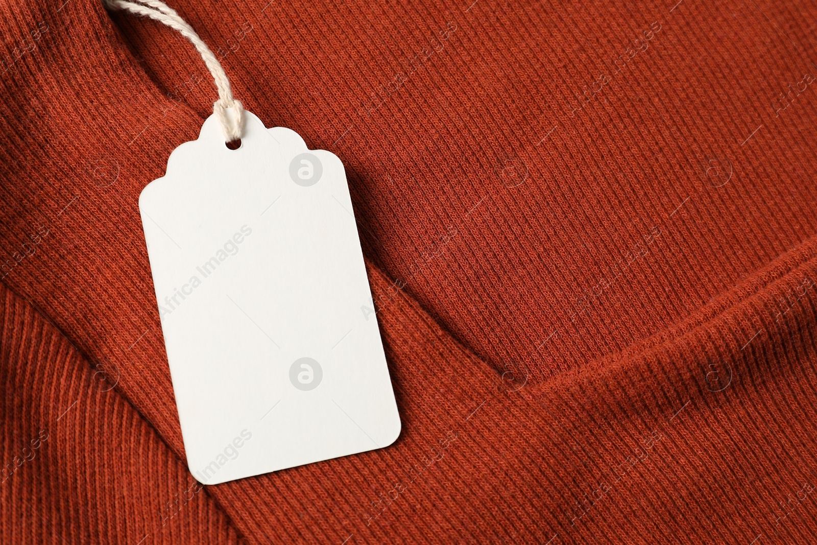 Photo of Cardboard tag on orange garment, top view